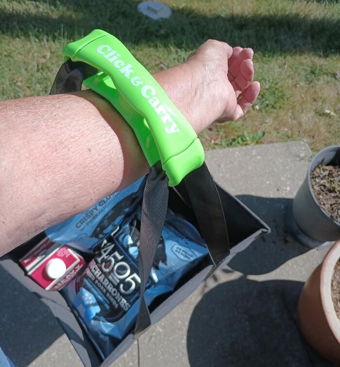 Green Click & Carry handle on arm lifting heavy grocery bag outdoors, showcasing brilliant Amazon finds for easy carrying.