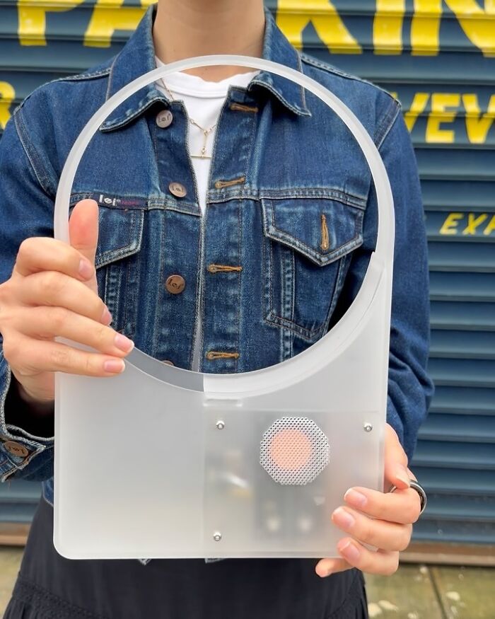 Person in a denim jacket holding an unusual accessory that blends everyday objects with fashion elements.