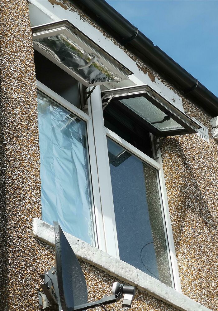 Old textured exterior wall with two windows open and plastic covering on one during heatwaves around the world