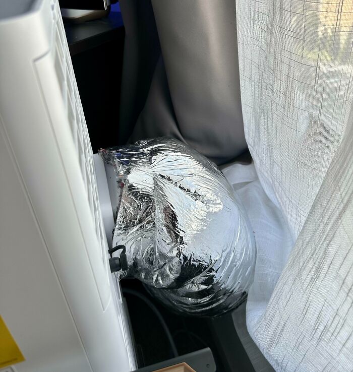 Silver insulated duct attached to a portable air conditioner showing a heatwave cooling setup indoors.
