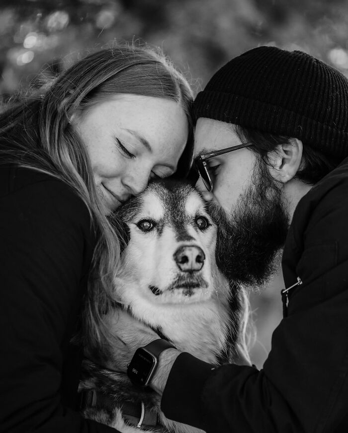 Black and white photo of a couple sharing a tender moment with their dog, capturing touching final moments between pets and humans.