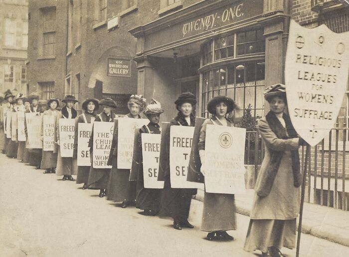 Women in the 20th century suffrage era marching with protest signs for voting rights and equality.