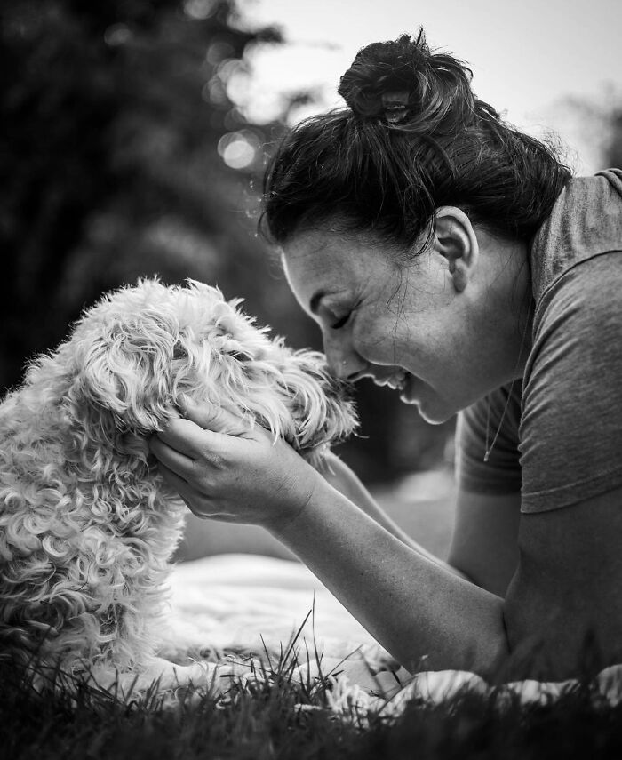 Woman tenderly holding and touching her dog's face, capturing a touching moment between pets and their humans.