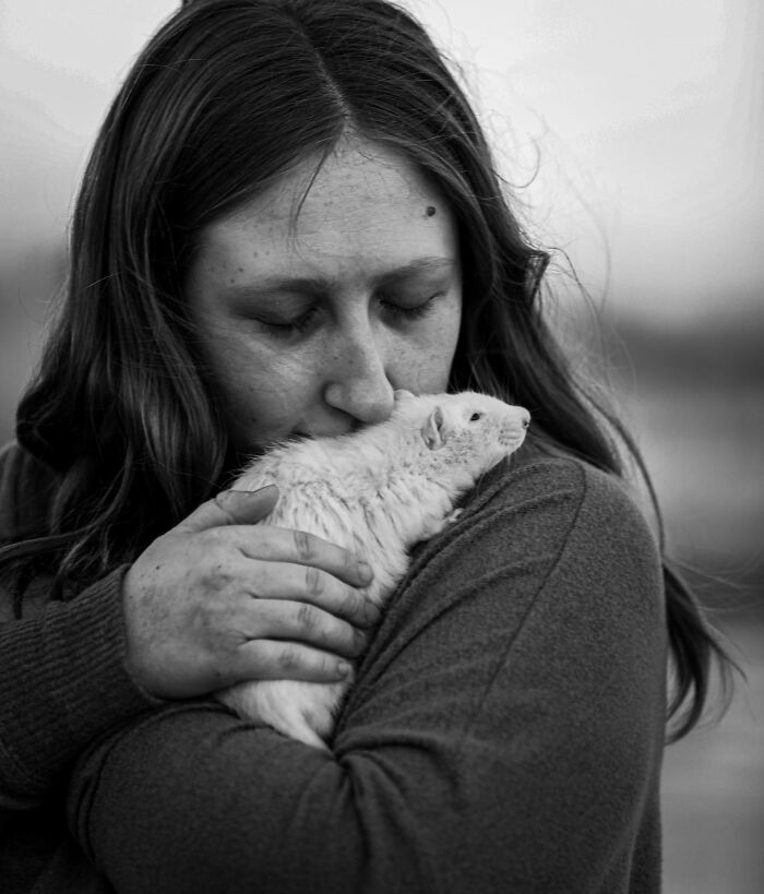 Woman gently holding and kissing her pet rat, capturing touching final moments between pets and their humans.