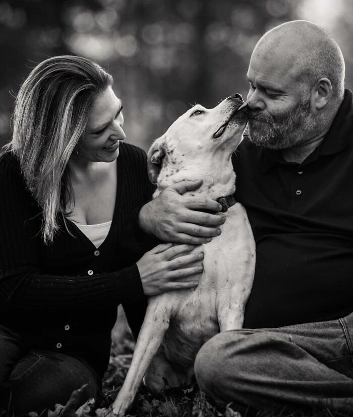 Couple sharing a tender moment with their dog, capturing touching final moments between pets and their humans outdoors.