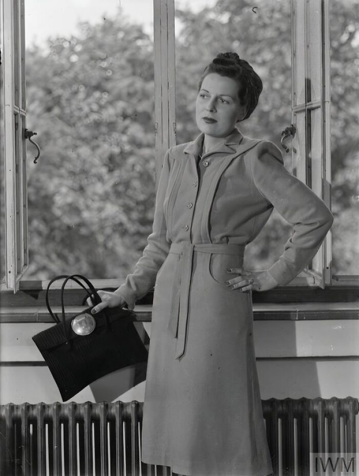 British woman in tailored coat with handbag, showcasing style during WWII restrictions by keeping fashion elegant and practical.