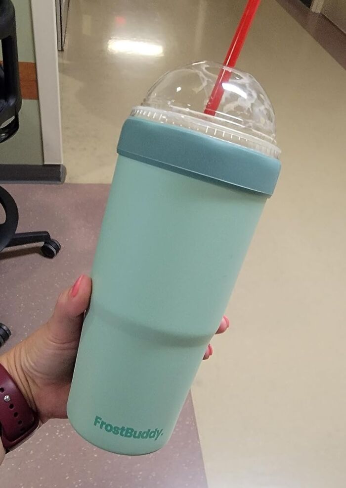 Hand holding a FrostBuddy insulated cup with a red straw, a useful heatwave hack for staying cool in summer.