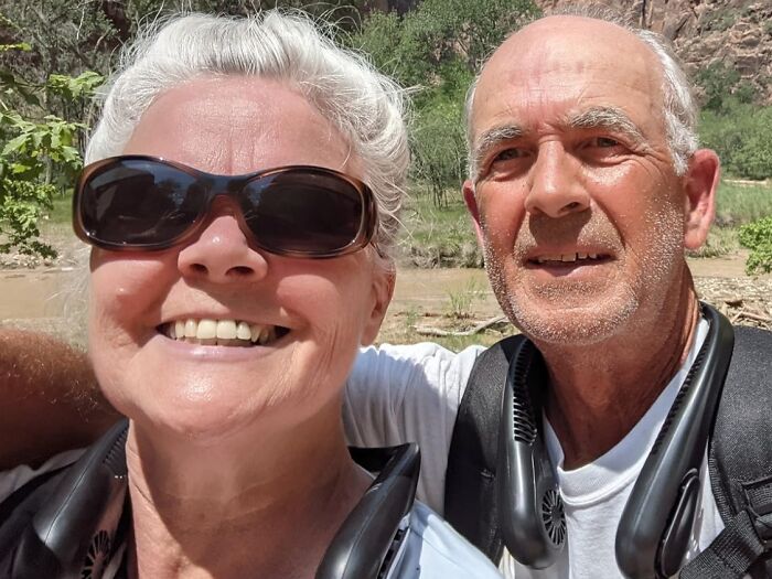 Older couple outdoors wearing cooling neck fans, enjoying a sunny day with heatwave hacks for summer comfort and relief.