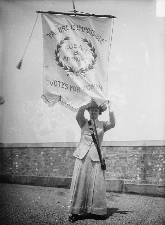 Woman holding a suffrage banner with Susan B. Anthony quote advocating votes for women in the 20th century era