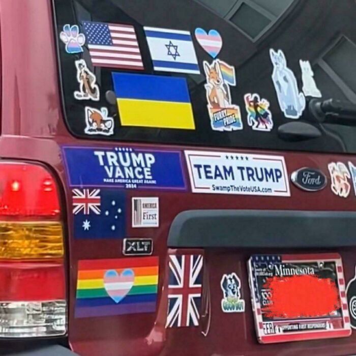 Red vehicle covered with conflicting political and pride stickers showing facepalm moments of absent basic logic.