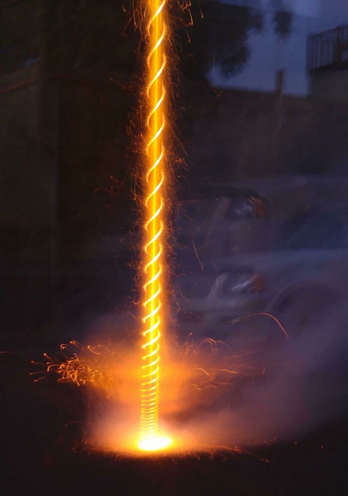 Vertical spiral of bright sparks and glowing light during a nighttime rare coincidence captured without Photoshop effects.