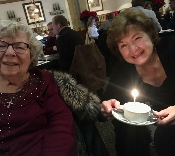 Two elderly women in a restaurant celebrating with a dessert featuring a candle, illustrating rare coincidences.