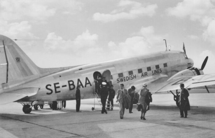 Passengers dressed in elegant attire boarding a vintage Swedish Airlines plane, showcasing flying as an affair of glamour.