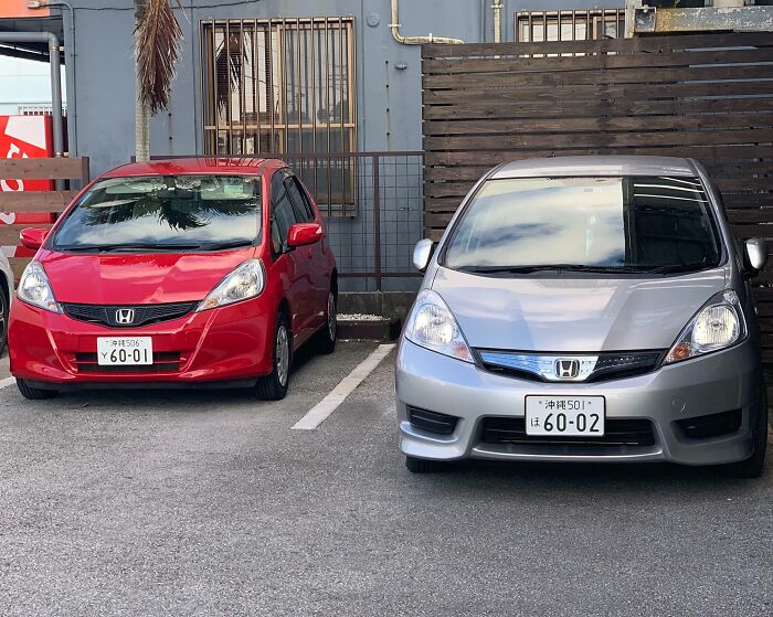 Two Honda cars parked side by side with license plates showing a rare coincidence in numbering.