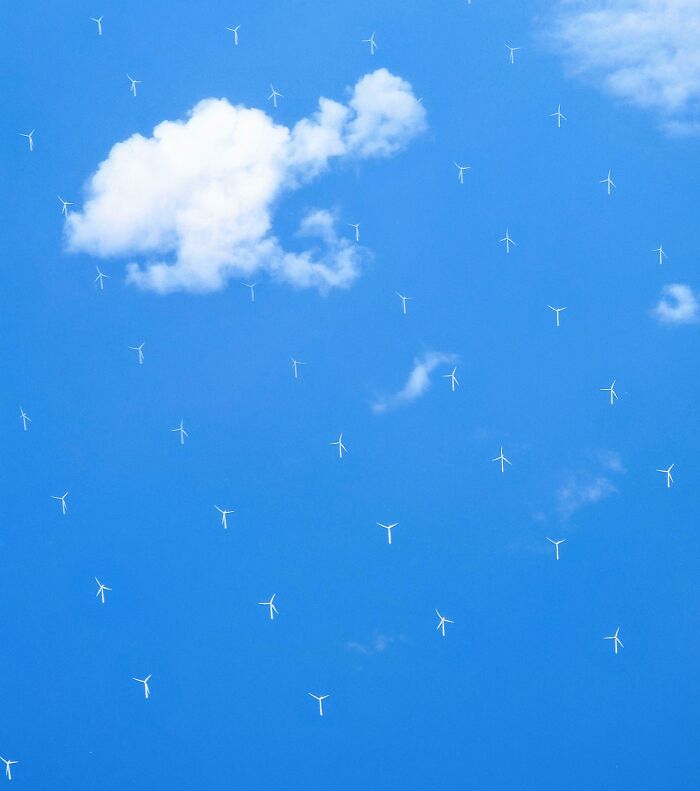 Cloud that looks like a wind turbine surrounded by many real wind turbines in a rare coincidence photo.