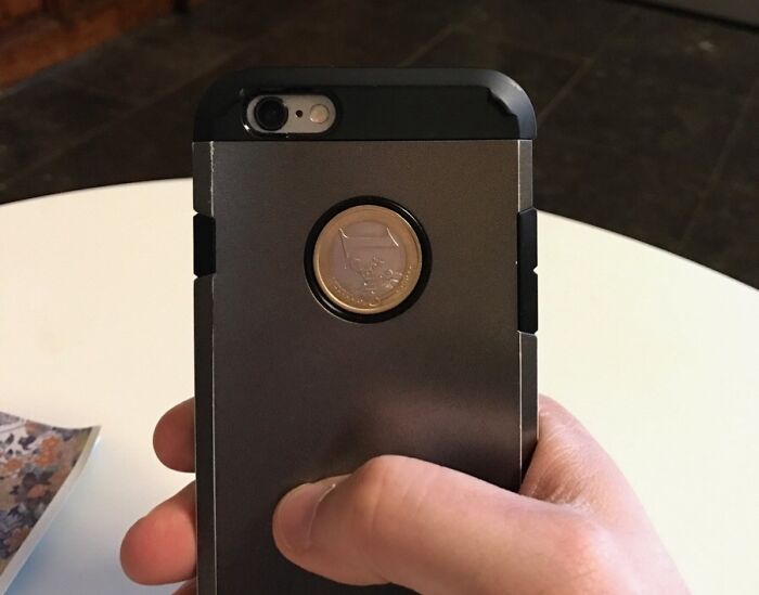 Close-up of a rare coincidence where a coin perfectly fits the circular cutout of a phone case.