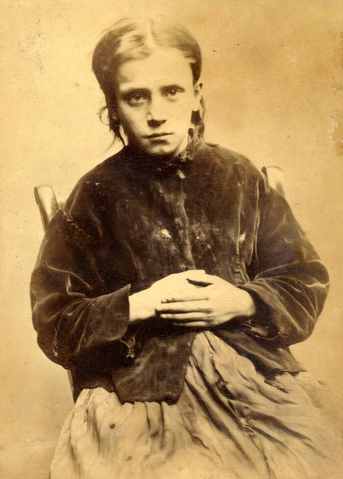 Vintage historical mugshot of a woman sitting with hands clasped, showing intriguing stories behind historical mugshots.