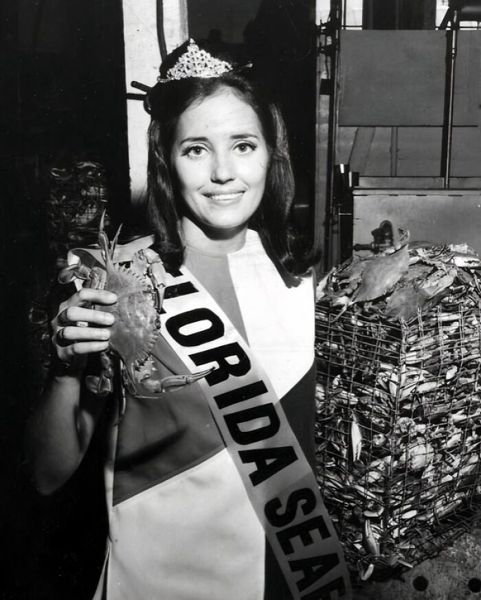 Woman in Florida wearing a tiara and sash holding a crab, representing women breaking barriers in the 1970s seafood industry.