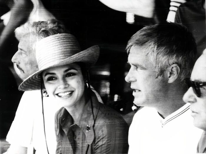Woman in Florida wearing a hat, smiling and engaging with men, captured in a black and white photo from the 1970s breaking barriers.