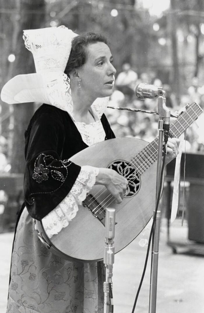 Woman in traditional costume playing guitar and singing into a microphone, representing women in Florida breaking barriers in the 1970s.