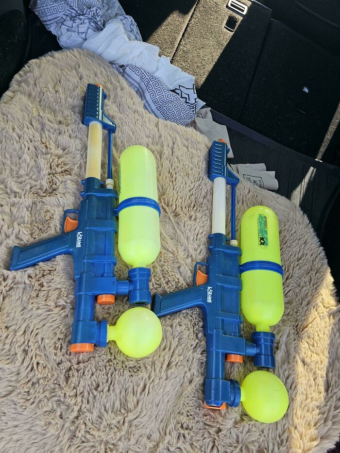 Two vintage blue and yellow water guns on a fuzzy blanket, evoking nostalgic 90s simpler, stranger days toys.