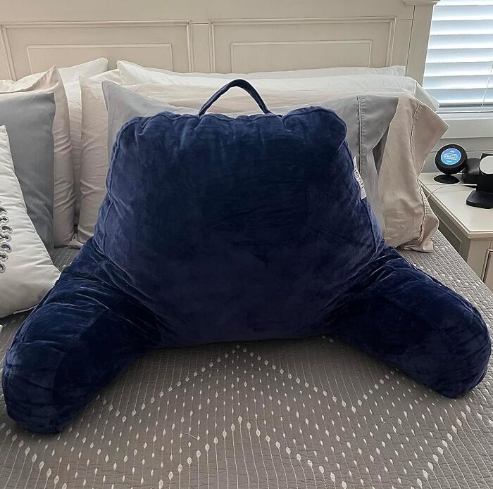 Large navy blue backrest pillow on a bed, a must-have dorm find to survive freshman year and beyond.
