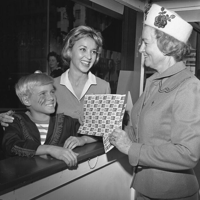 LA women in 1962 smiling and interacting with a child in costume, showcasing joyful moments from the era.
