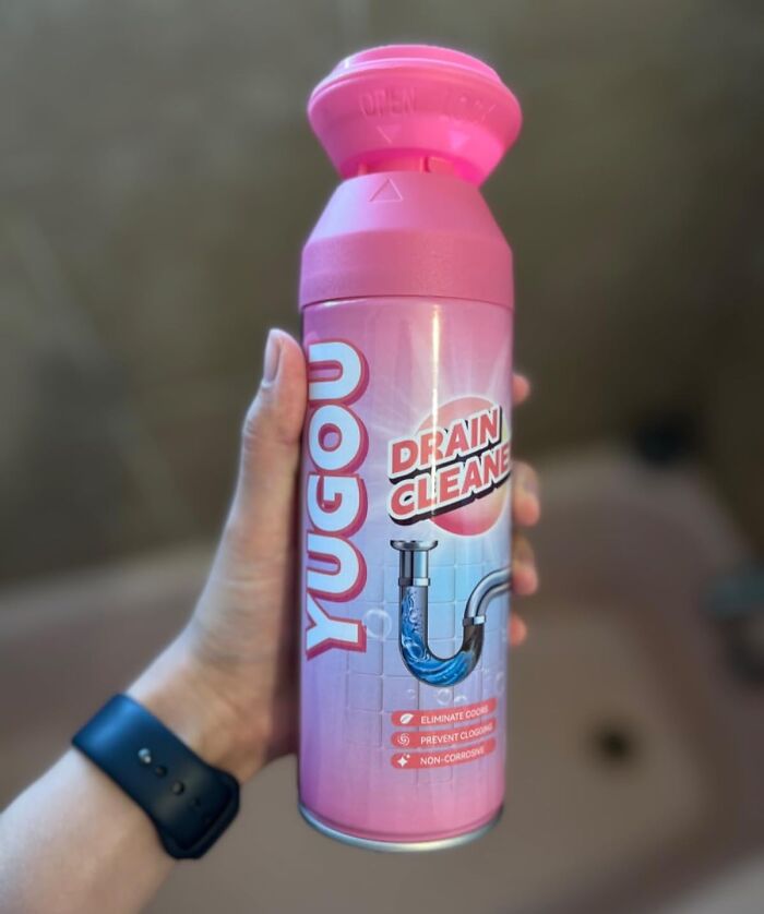 Hand holding a pink drain cleaner bottle, showcasing a genius gadget for tackling everyday household problems.