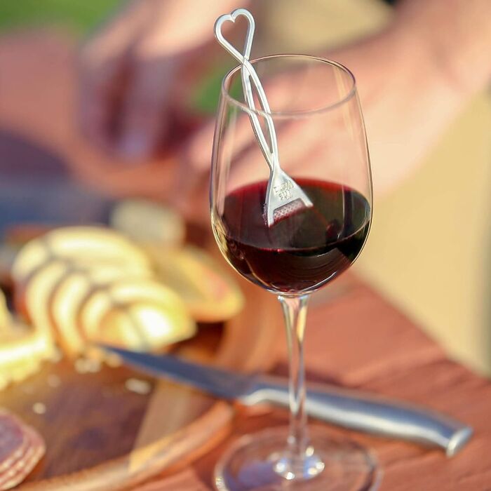 Wine glass with a small fork gadget featuring a heart-shaped handle for easy wine tasting and food pairing.