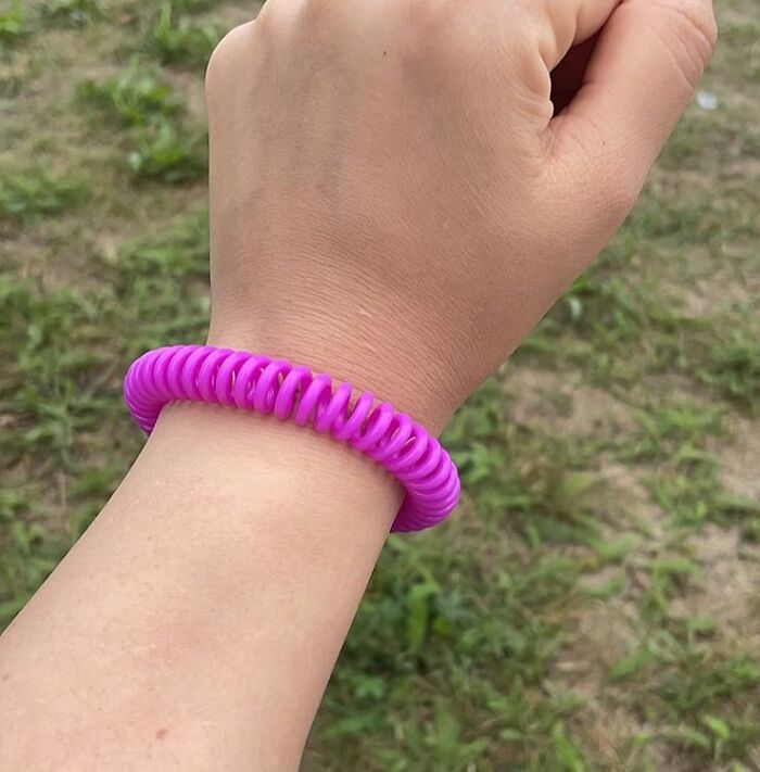 A hand wearing a pink coil gadget wristband designed for tackling daily dumb problems outdoors.