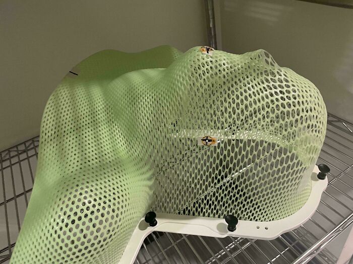 Green mesh radiation mask shaped to fit a head and neck, used in medical treatment of the human body.