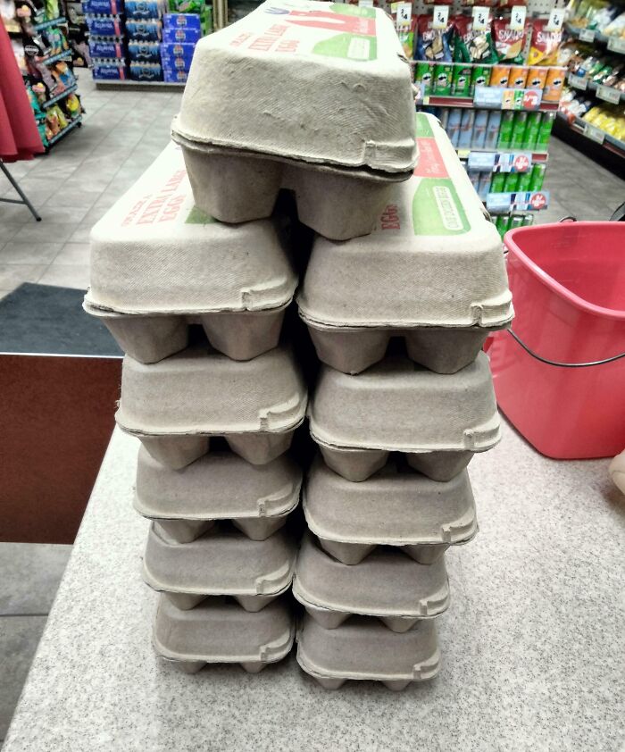 Cajas apiladas de cartón para huevos en mostrador de tienda, reflejando aumento del consumismo moderno.