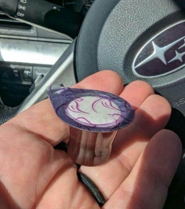 Hand holding a crushed single-use coffee pod inside a car, highlighting waste from consumerism habits.
