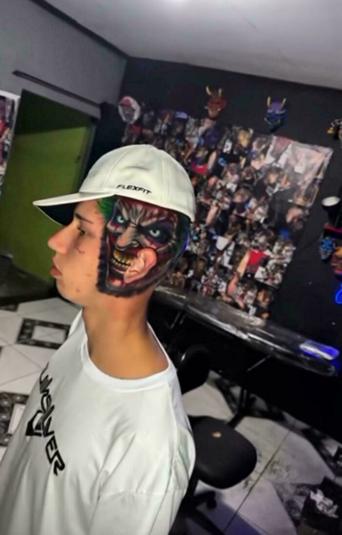 Young man with an intricate face tattoo showing a devilish character, an example of awful taste but great e*******n tattoo art.