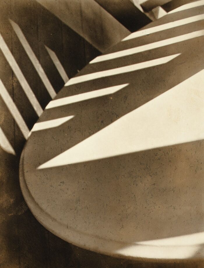 Abstract vintage photo of light and shadow patterns on a curved wooden surface, highlighting 20th century triumph and tragedy.
