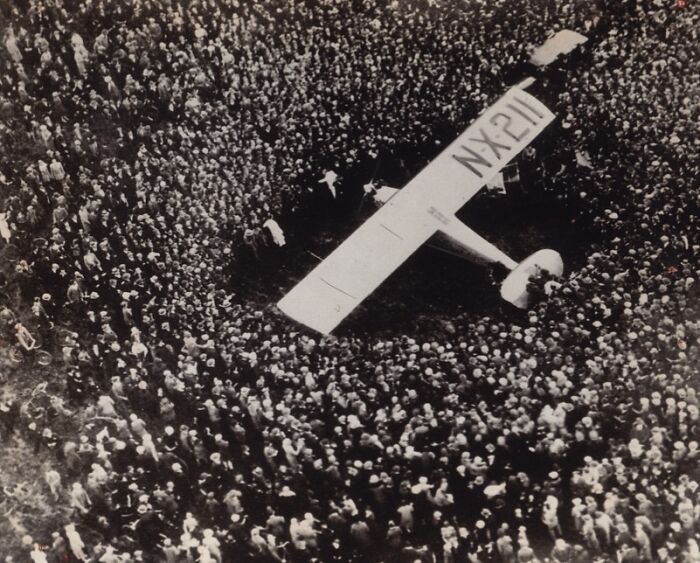 Crowd gathered around the NX-211 airplane, a historic moment capturing the triumph and tragedy of the 20th century.