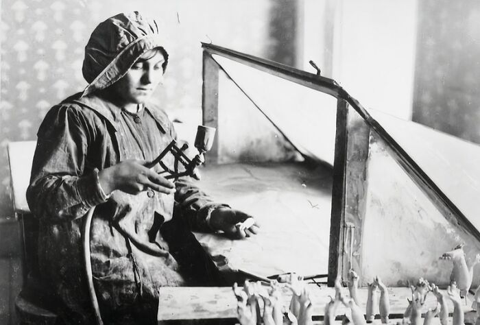 Woman in protective clothing working with a spray gun in a factory, showing how women changed everything during WWI.