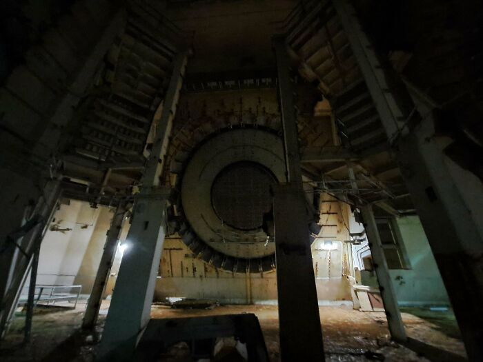 Interior of an abandoned, extremely large facility with a massive circular structure, evoking a scary and eerie feeling.