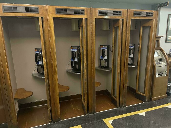 Wooden vintage phone booths with old payphones and small wooden seats, evoking nostalgic memories of past decades.