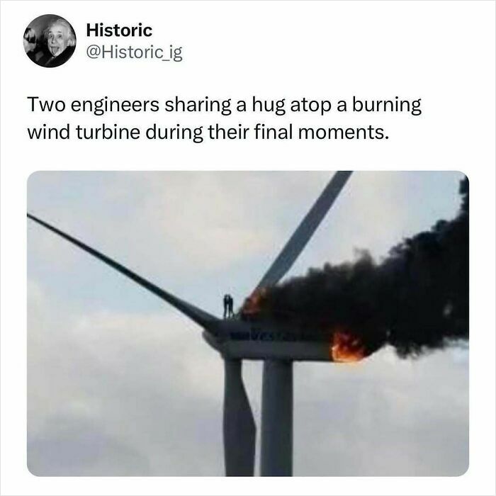 Two engineers hugging atop a burning wind turbine, a striking and emotional historic photo capture.