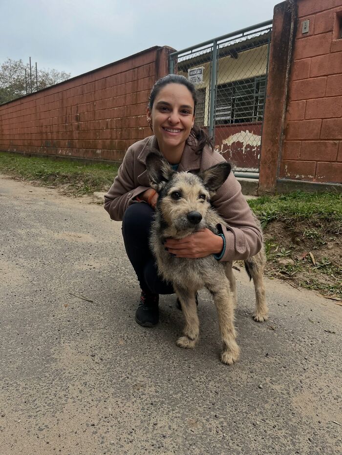 Woman smiling and hugging a joyful shelter dog during one of their weekly walks outside the shelter.