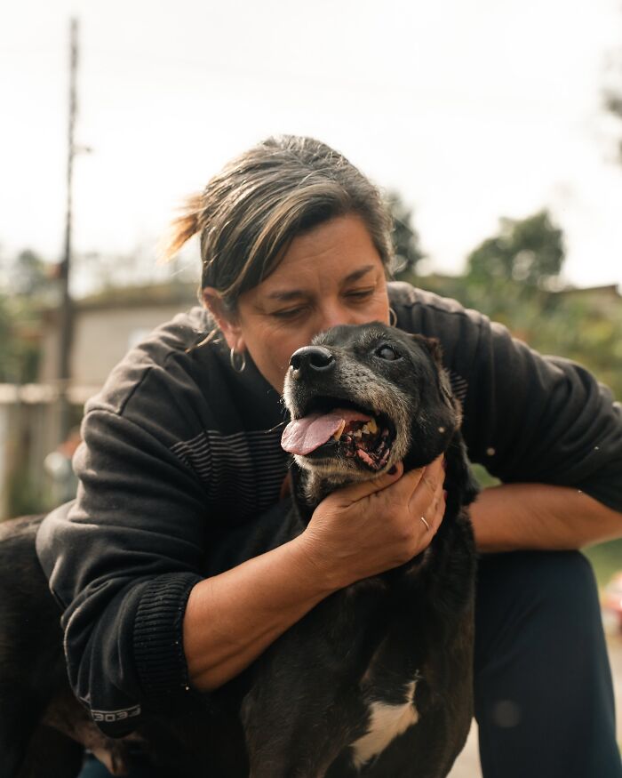Woman showing affection to a happy shelter dog, capturing the pure joy of shelter dogs on their weekly walks outdoors.