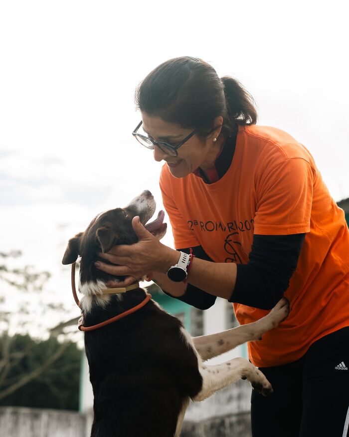 Woman smiling and playing with a happy shelter dog outdoors, capturing the pure joy of shelter dogs on their walks.