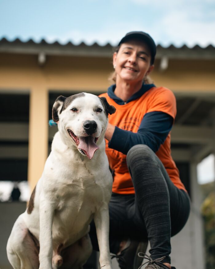 Woman in orange shirt with a happy shelter dog enjoying a joyful moment on their weekly walk outside.