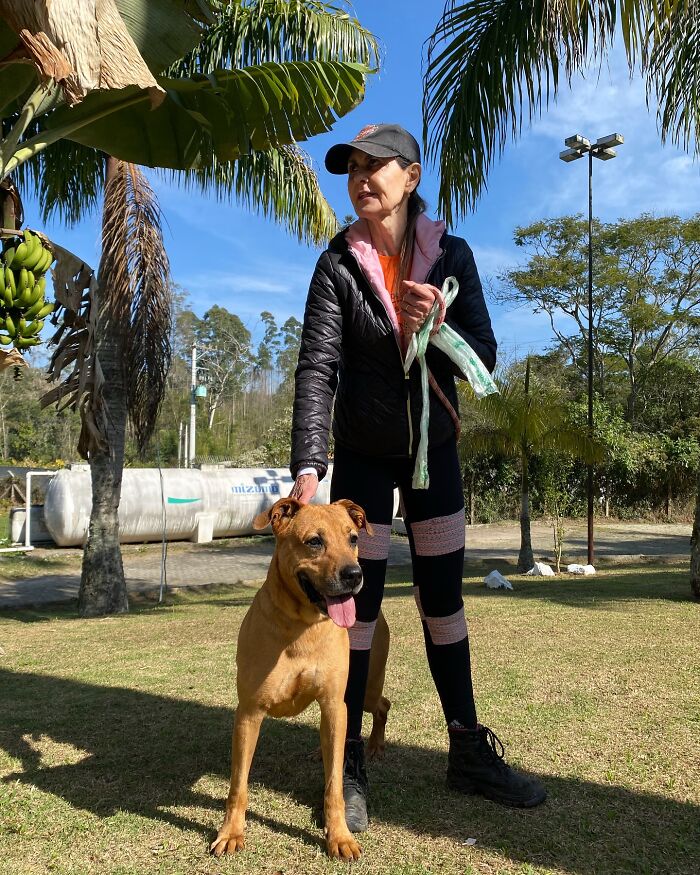 Woman with a shelter dog enjoying the outdoors during a joyful weekly walk on a sunny day.