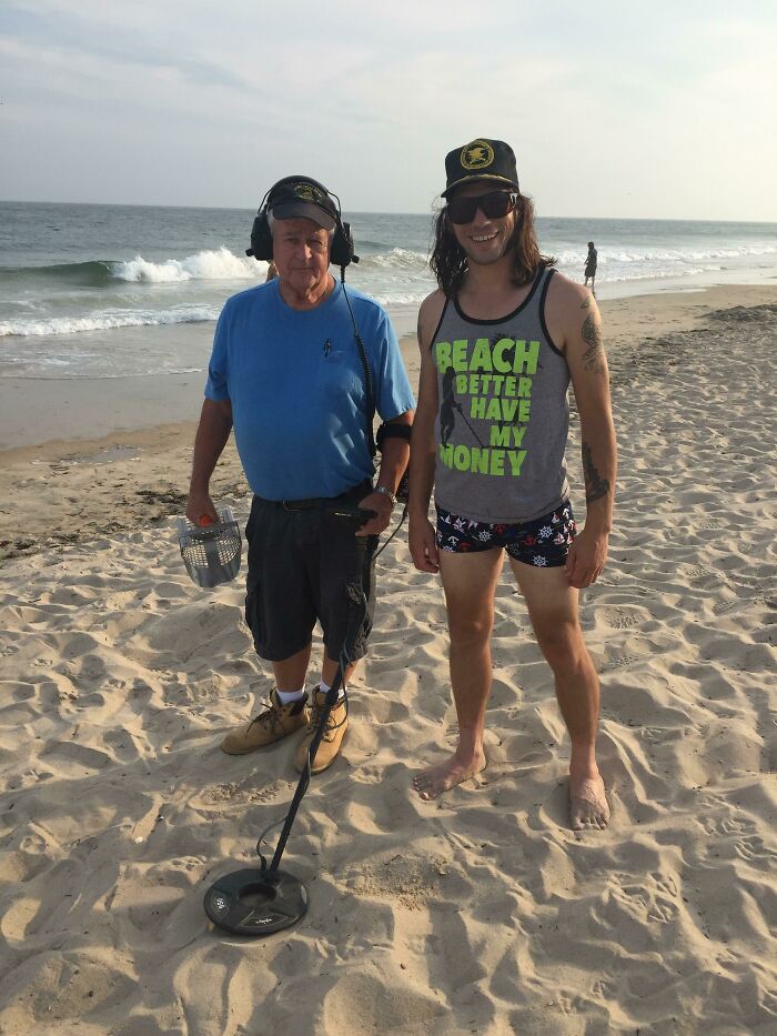Two men on a beach using a metal detector, a humorous vacation pic that fits comedy special moments.