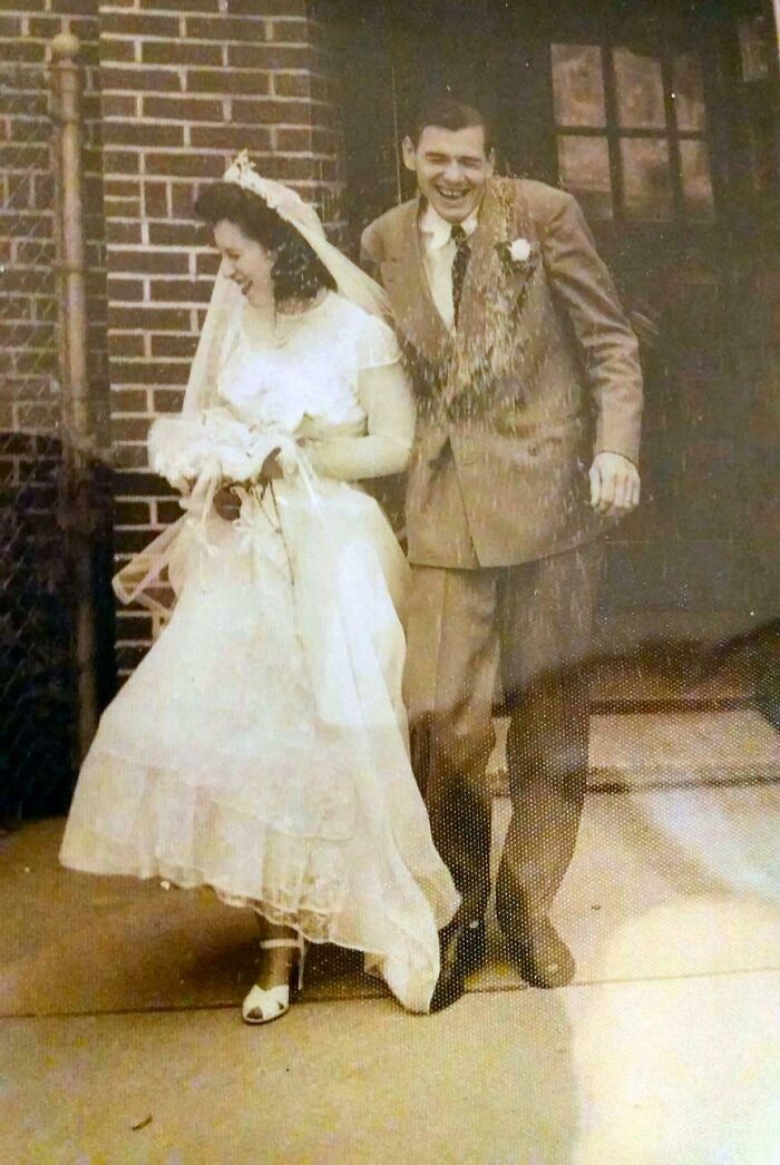 Vintage candid wedding photo capturing joyful couple outside a brick building showing candid glimpses into the past.