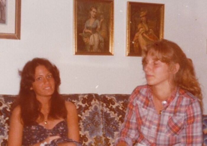 Two women from the 70s sitting on a patterned couch, showcasing everyday life and fashion of women in the 70s.