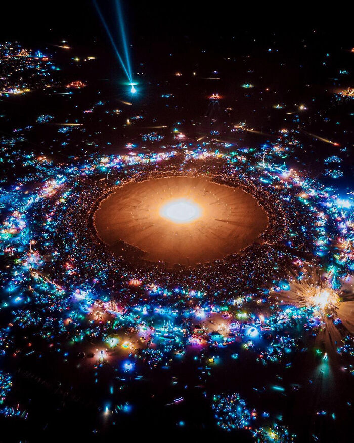 Aerial view of a large, illuminated desert gathering, showcasing extremely large things and eerie night lights.
