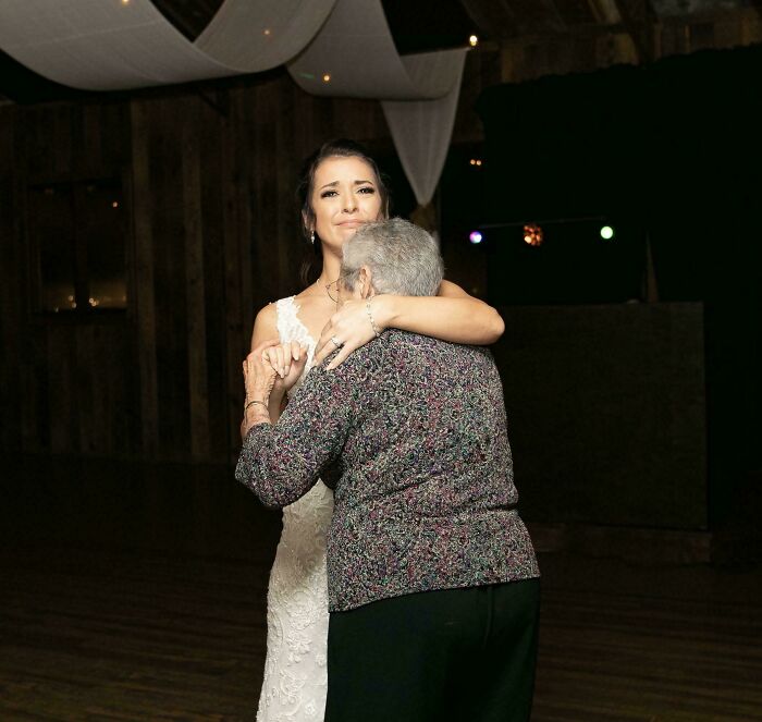 Young woman in a white dress sharing an emotional dance with an elderly woman in a dimly lit room accidental renaissance photo